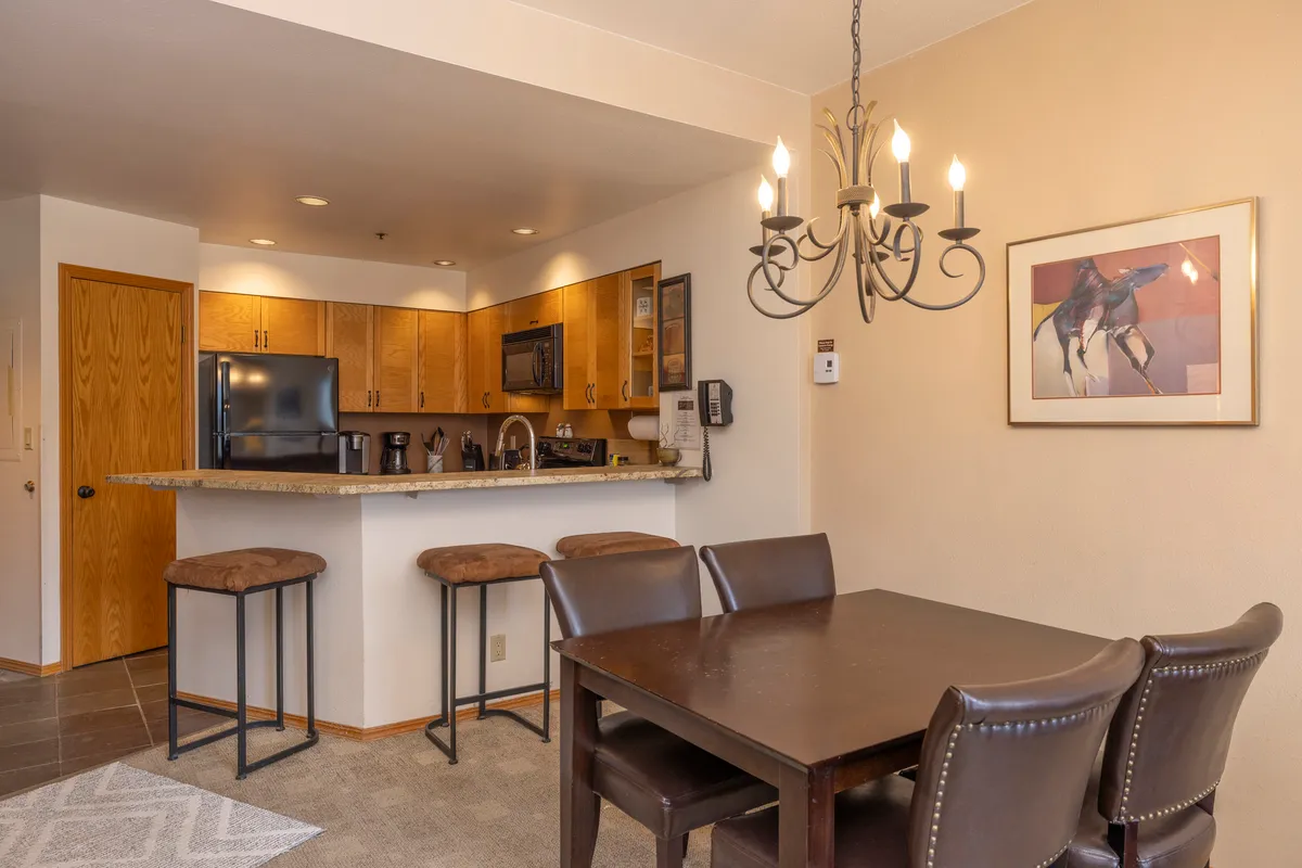 A cozy kitchen island is complemented by a chandelier and an adjoining dining table, creating a seamless transition between food prep and communal dining. The setting suggests an inviting space for family meals, holiday gatherings, and intimate dinners.