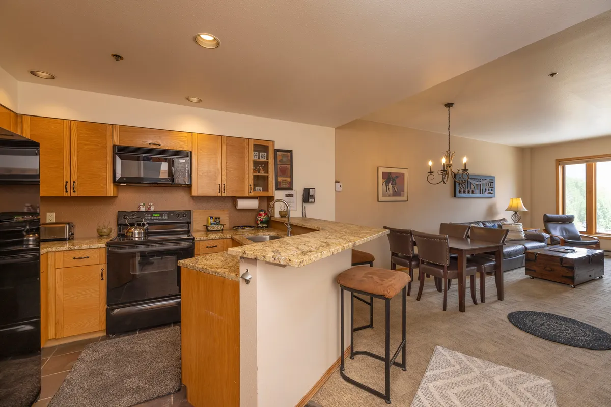 The image showcases the inviting interior of Kendall 444, with a well-equipped kitchen, a dining area perfect for shared meals, and a cozy seating space ideal for relaxing after a day of mountain adventures. Large windows hint at mountain views, and the overall ambiance is welcoming and intimate, suited for couples or small families.